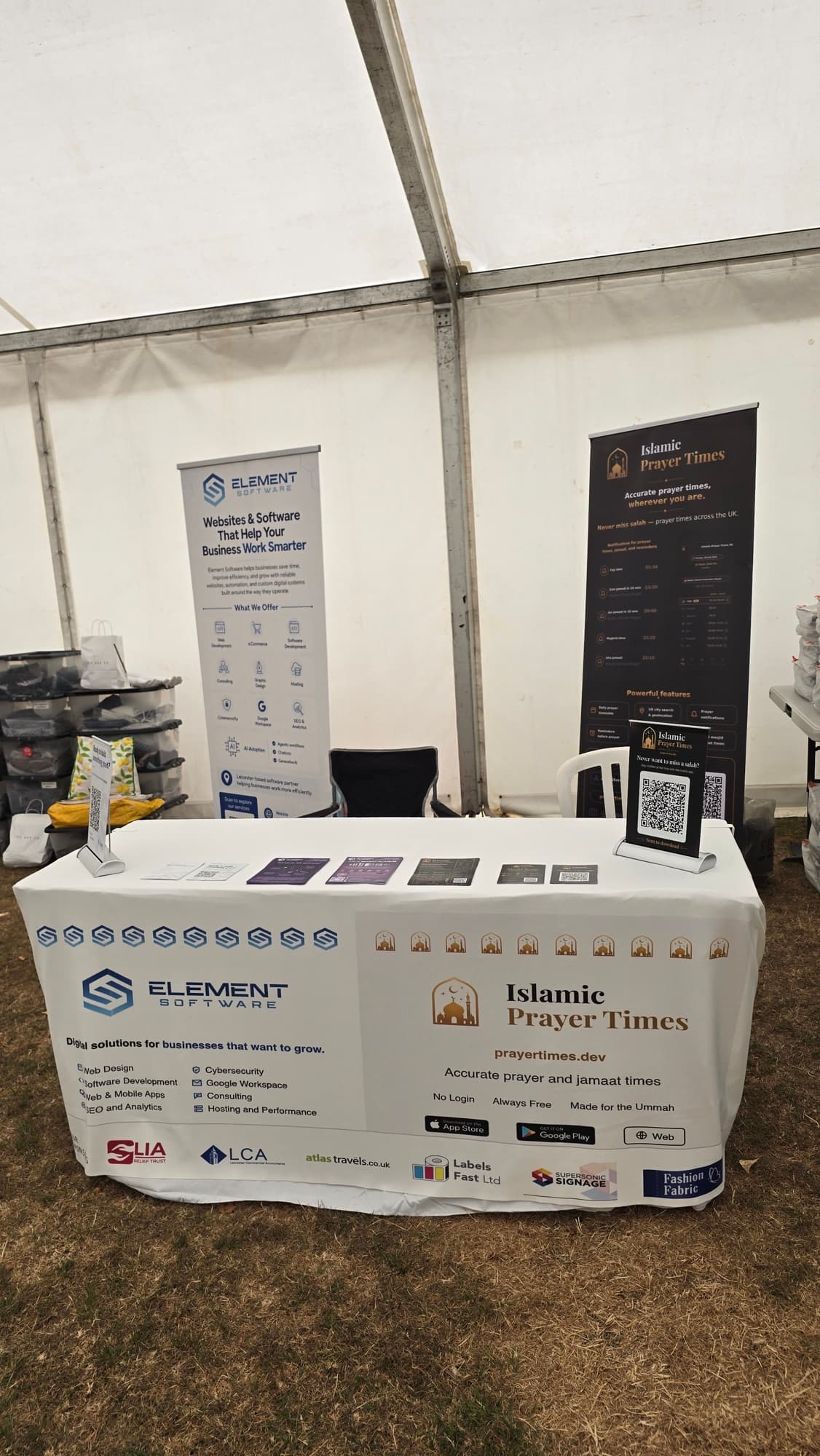 Element Software and Islamic Prayer Times stall inside a marquee, with sponsor logos printed along the bottom of the tablecloth